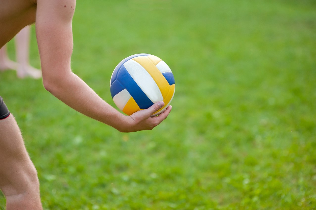 Teen boy playing beach volleyball. Volleyball player on the grass playing with the ball, a volleyball ball in his hand.